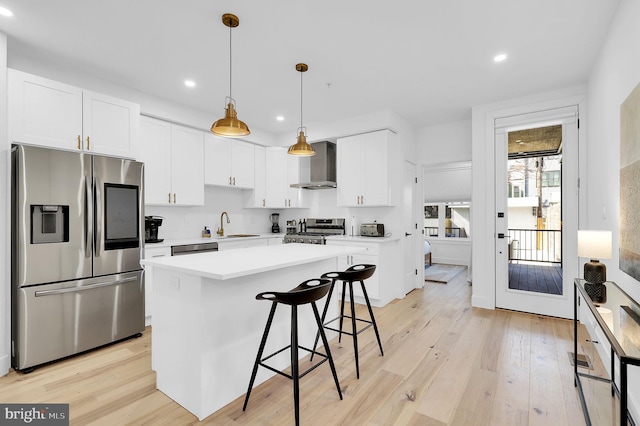 kitchen with white cabinetry, light countertops, appliances with stainless steel finishes, wall chimney exhaust hood, and pendant lighting