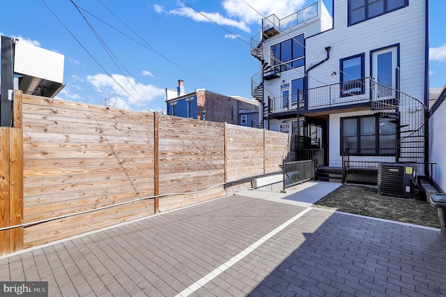 view of patio / terrace featuring stairway, fence, and cooling unit