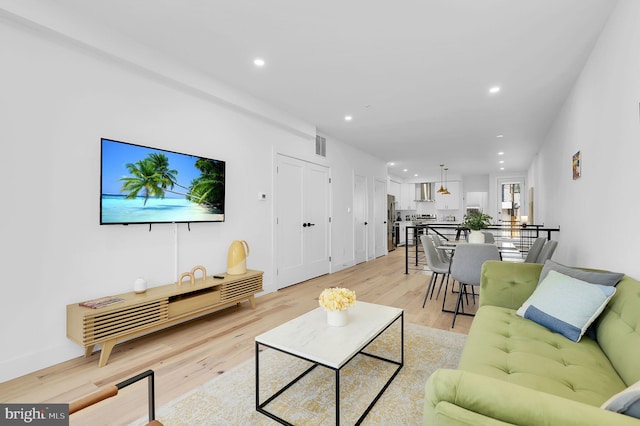 living room with light wood-type flooring, visible vents, and recessed lighting