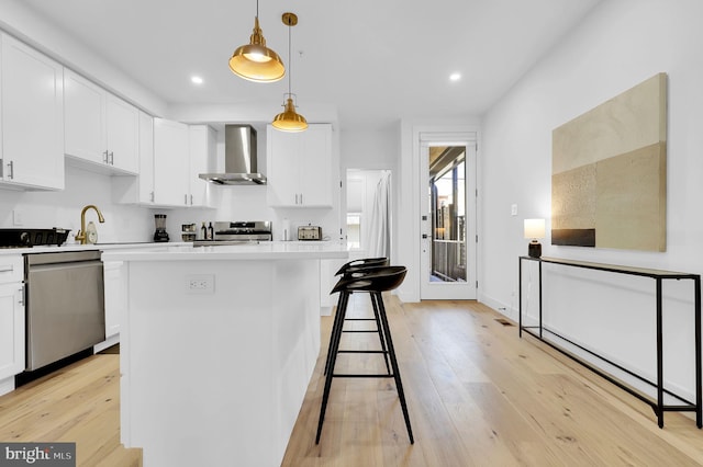 kitchen featuring wall chimney exhaust hood, white cabinetry, stainless steel appliances, and light countertops