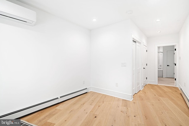 empty room with wood-type flooring, a wall mounted air conditioner, and baseboard heating