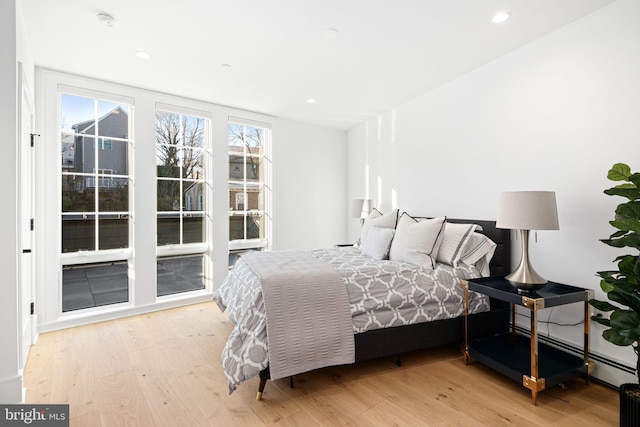 bedroom with a baseboard radiator and light wood-type flooring