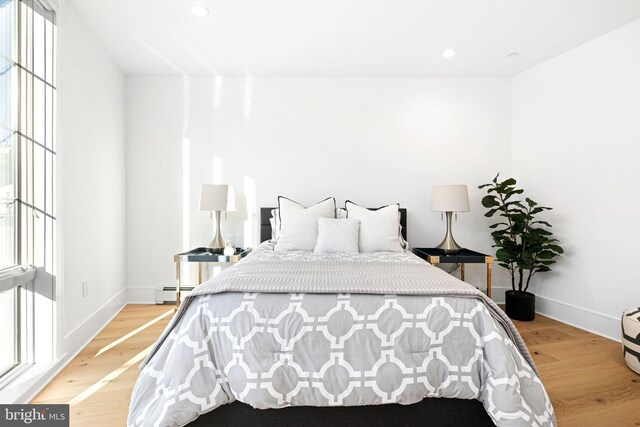 bedroom featuring a baseboard radiator and light hardwood / wood-style flooring