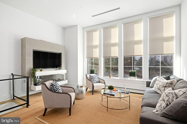 living room with a baseboard heating unit and light hardwood / wood-style flooring