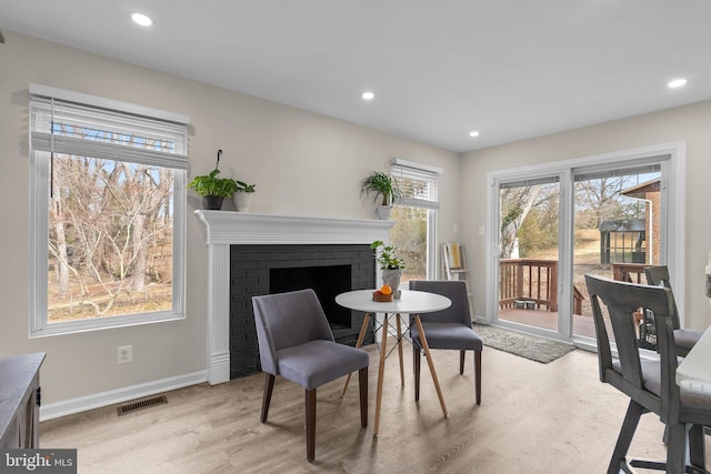 sitting room with a brick fireplace and light hardwood / wood-style flooring