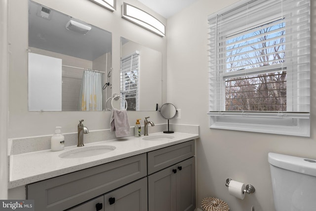 bathroom with a shower with shower curtain, vanity, toilet, and a healthy amount of sunlight