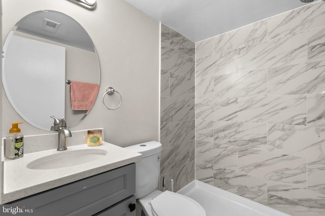 bathroom featuring vanity, tiled shower, and toilet