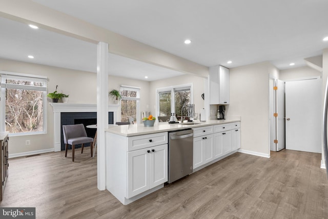 kitchen featuring a brick fireplace, sink, light wood-type flooring, white cabinetry, and dishwasher