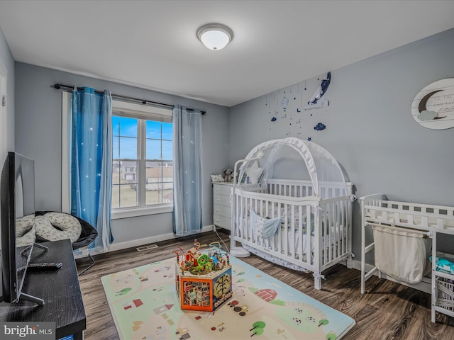 bedroom with dark hardwood / wood-style floors and a crib