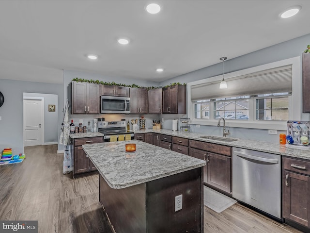 kitchen featuring sink, decorative light fixtures, dark brown cabinets, appliances with stainless steel finishes, and a kitchen island