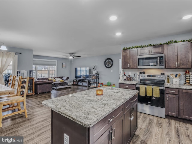 kitchen with dark brown cabinetry, a center island, light wood-type flooring, ceiling fan, and stainless steel appliances