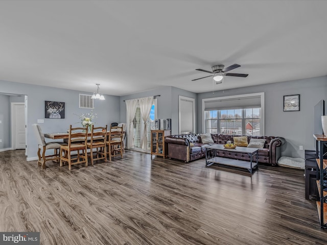 living room with a healthy amount of sunlight, wood-type flooring, and ceiling fan with notable chandelier