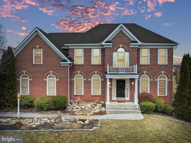 view of front of house with a balcony and a yard