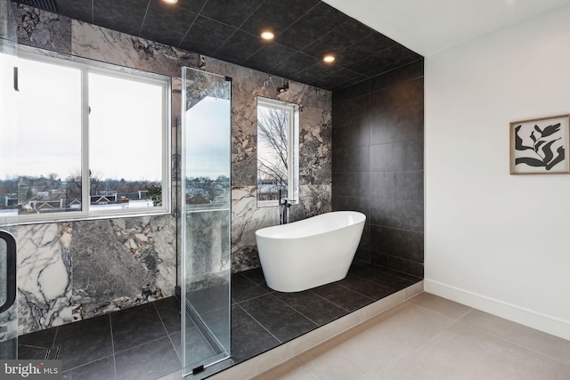 bathroom with a bath, tile patterned floors, and tile walls