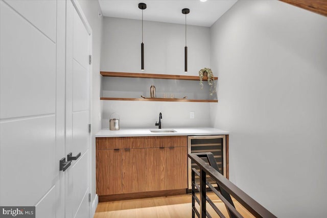 bar with sink, hanging light fixtures, and light wood-type flooring