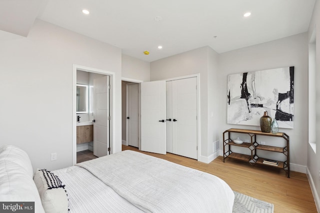 bedroom with a closet, connected bathroom, and light hardwood / wood-style flooring