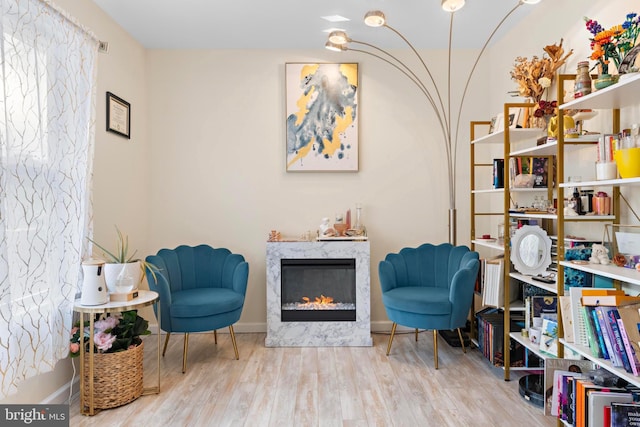 living area with a high end fireplace and light hardwood / wood-style flooring