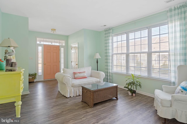 living room with wood finished floors, visible vents, and baseboards