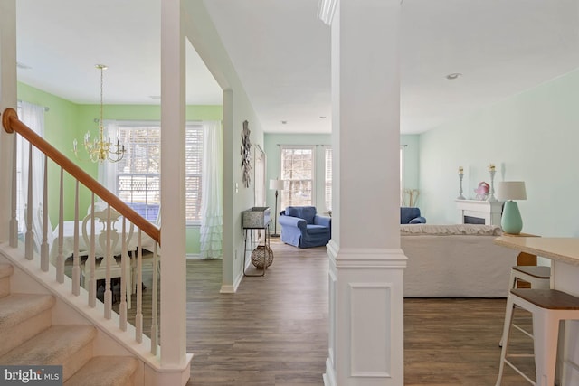 entrance foyer featuring baseboards, dark wood finished floors, stairs, a fireplace, and a chandelier