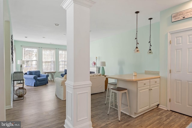 kitchen featuring decorative columns, open floor plan, wood finished floors, and light countertops