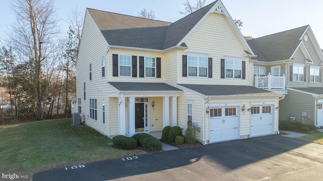 view of front of house with driveway, roof with shingles, an attached garage, a front lawn, and central AC