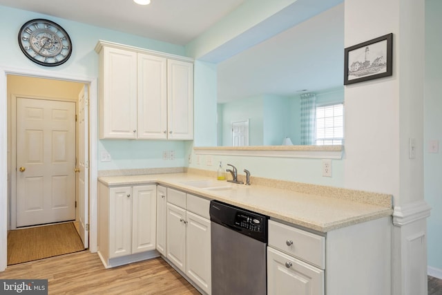 kitchen featuring white cabinets, light countertops, light wood-type flooring, stainless steel dishwasher, and a sink