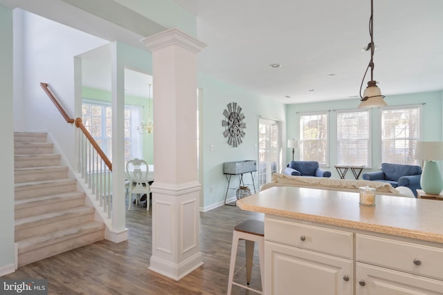 kitchen with dark wood-style floors, a kitchen breakfast bar, open floor plan, light countertops, and ornate columns