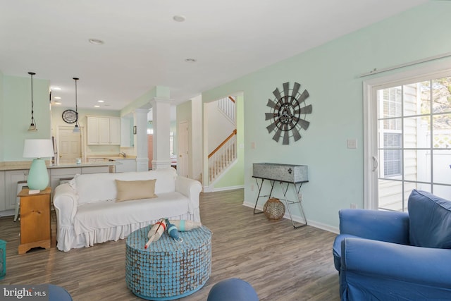 living room with decorative columns, recessed lighting, stairway, wood finished floors, and baseboards