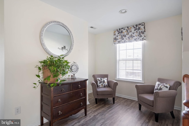 living area featuring wood finished floors, visible vents, and baseboards