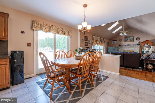 tiled dining area featuring a notable chandelier and vaulted ceiling with skylight