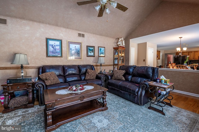 living room with lofted ceiling, hardwood / wood-style flooring, and ceiling fan with notable chandelier