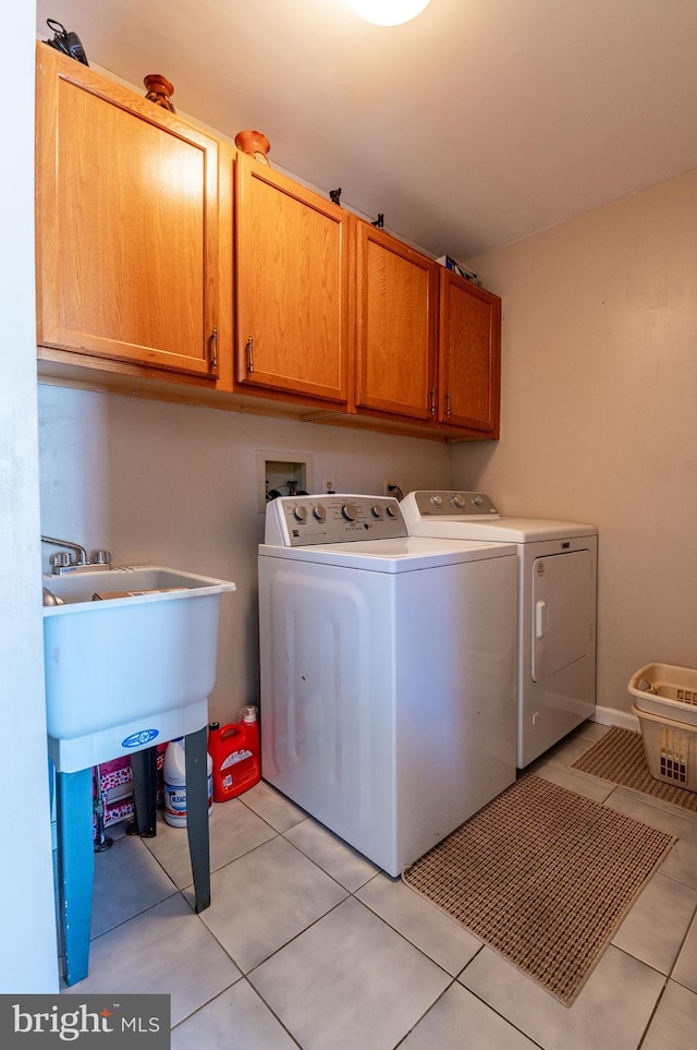 laundry area featuring light tile patterned flooring, cabinets, and washer and clothes dryer