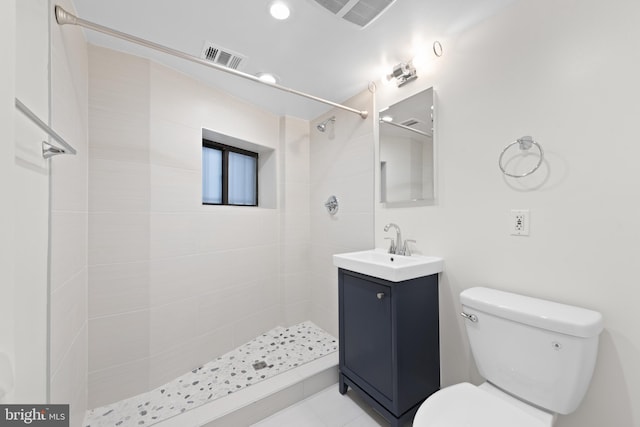 bathroom featuring tiled shower, vanity, and toilet