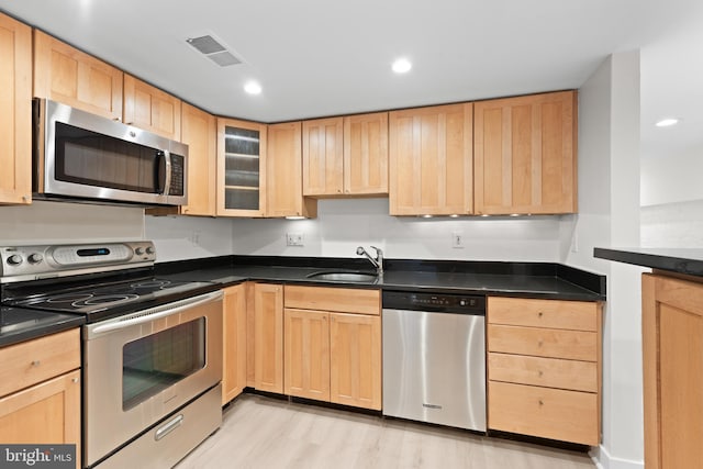 kitchen with light brown cabinetry, sink, light wood-type flooring, and appliances with stainless steel finishes