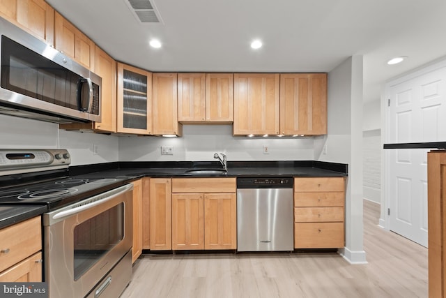 kitchen featuring stainless steel appliances, light brown cabinetry, light hardwood / wood-style floors, and sink