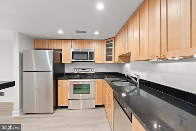 kitchen with stainless steel appliances, sink, light brown cabinets, and light wood-type flooring