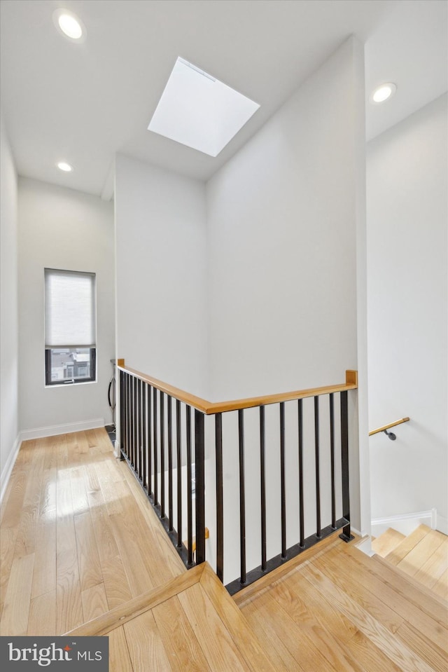 hall with hardwood / wood-style floors and a skylight