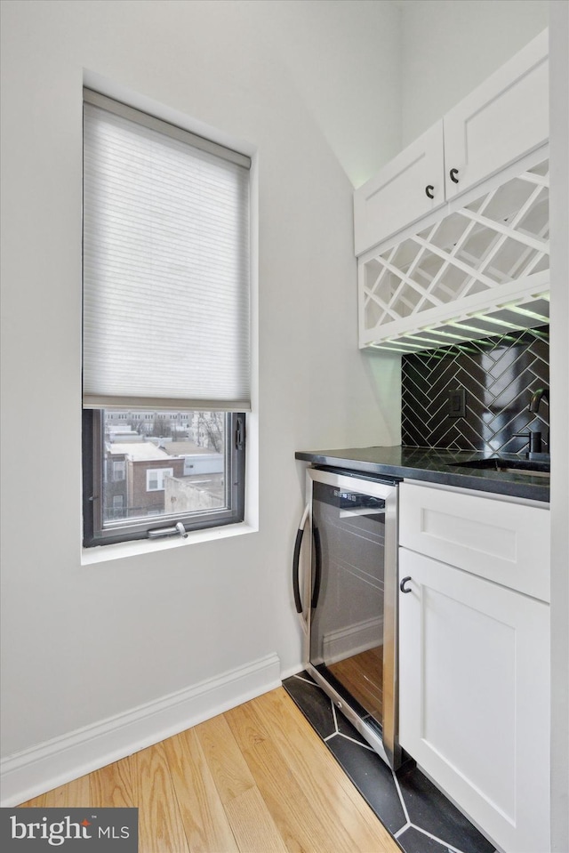 washroom with hardwood / wood-style floors, beverage cooler, and bar area