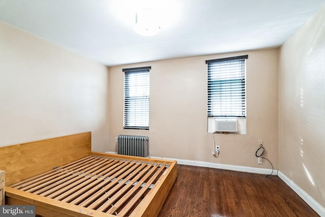 unfurnished bedroom with cooling unit, dark hardwood / wood-style floors, and radiator