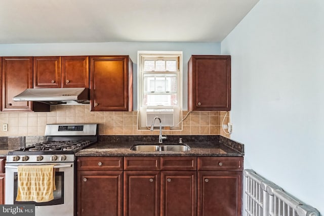 kitchen featuring sink, tasteful backsplash, stainless steel range with gas cooktop, radiator, and dark stone counters