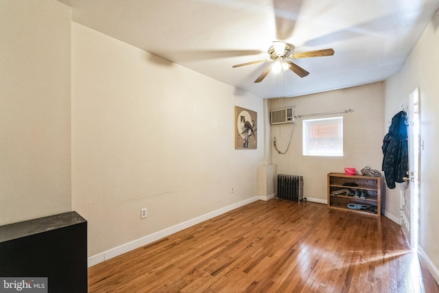 unfurnished bedroom with hardwood / wood-style flooring, ceiling fan, a wall mounted air conditioner, and radiator