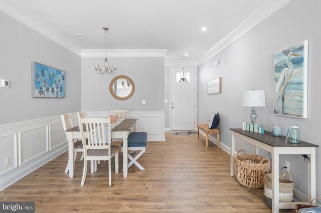 dining room with light wood-type flooring, a chandelier, and crown molding