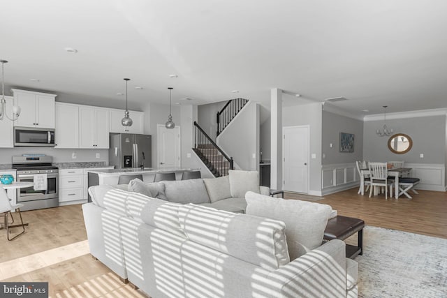 living room featuring crown molding, a notable chandelier, and light hardwood / wood-style floors