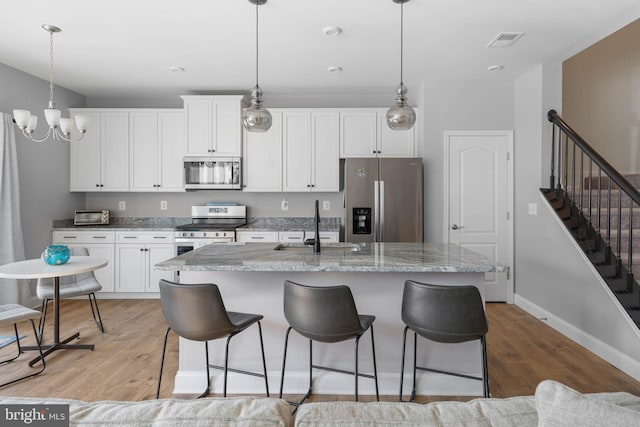 kitchen with a center island with sink, light hardwood / wood-style floors, sink, appliances with stainless steel finishes, and white cabinets