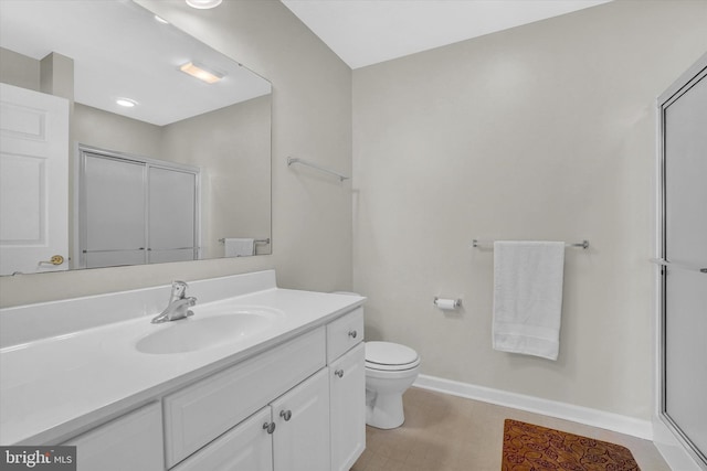 bathroom featuring vanity, toilet, and a shower with shower door