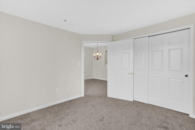 unfurnished bedroom with an inviting chandelier, carpet floors, and a closet