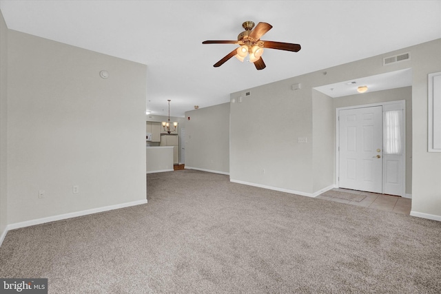 unfurnished living room featuring ceiling fan with notable chandelier and light carpet