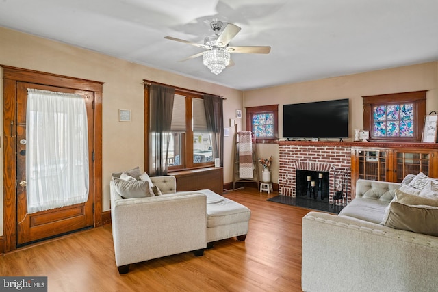 living room featuring a fireplace, light hardwood / wood-style floors, and ceiling fan