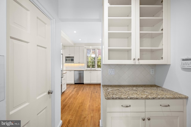 kitchen with light stone counters, tasteful backsplash, stainless steel appliances, and white cabinets