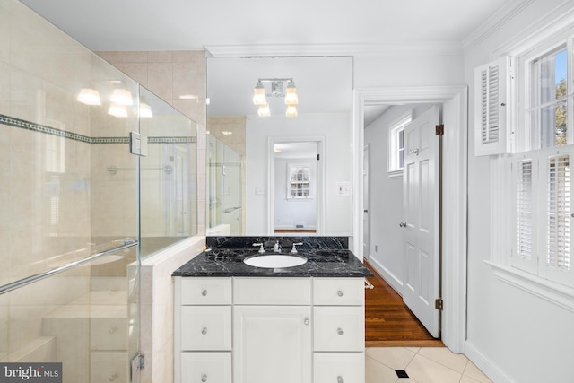 bathroom with tile patterned flooring, ornamental molding, an enclosed shower, and vanity